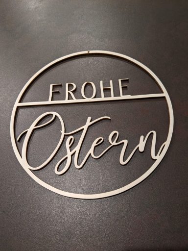Schmuckstück mit der Aufschrift "Frohe Ostern" in geschwungener Schrift.